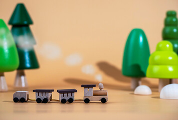 A small wooden locomotive on the background of wooden trees. Travel concept. Eco-friendly wooden toys.