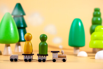 A small wooden locomotive carries wooden figurines of men. Travel concept. Eco-friendly wooden toys.