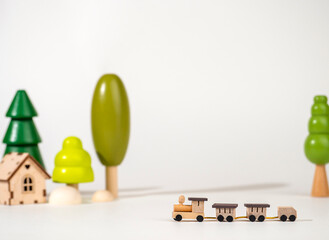 A small wooden locomotive on the background of wooden trees. Travel concept. Eco-friendly wooden toys.