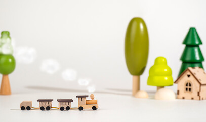 A small wooden locomotive on the background of wooden trees. Travel concept. Eco-friendly wooden toys.