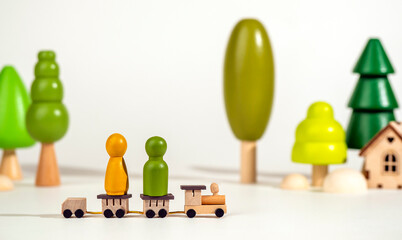 A small wooden locomotive carries wooden figurines of men. Travel concept. Eco-friendly wooden toys.