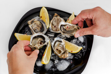 Oysters with lemon. Served black plate. White background.
