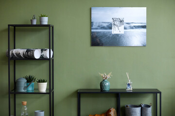 Horizontal image of domestic room with modern painting on green wall and shelves with design objects