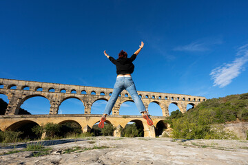 Vrouw die voor Pont du Gard, Frankrijk springt