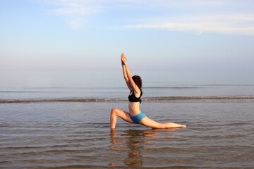 young girl while doing gymnastic exercises and stretching by the sea in the summer inside the water