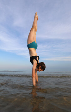 slender girl performs balance exercises with her head upside down and long legs high