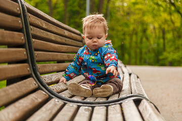 portrait of a little boy in the park on a bench catching soap bubbles