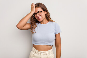 Young caucasian woman isolated on blue background forgetting something, slapping forehead with palm...
