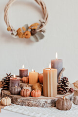 Fototapeta na wymiar Autumn table decoration. Interior decor for fall holidays with handmade pumpkins and candles. Holiday greeting card