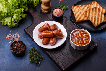 Traditional English breakfast with eggs, toast, sausages, beans, spices and herbs on a grey ceramic plate