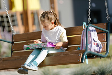 Happy schoolgirl with a backpack smiling and reading notes in notebooks