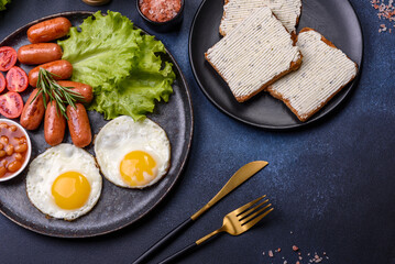 Traditional English breakfast with eggs, toast, sausages, beans, spices and herbs on a grey ceramic plate