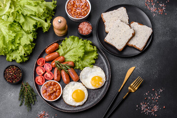 Fototapeta na wymiar Traditional English breakfast with eggs, toast, sausages, beans, spices and herbs on a grey ceramic plate