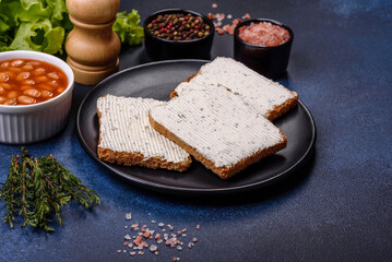 Traditional English breakfast with eggs, toast, sausages, beans, spices and herbs on a grey ceramic plate