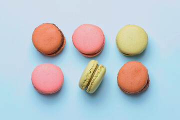 six macaroons in pink, green and brown against blue background