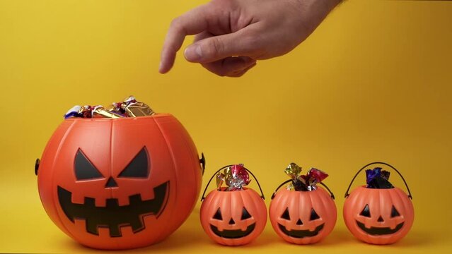 Slow motion shot of hand picking candy from halloween pumpkin basket