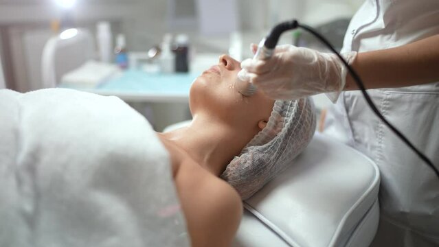 Lovely caucasian female getting a RF face lifting skin, tightening procedure at a cosmetology clinic. Non surgery, hardware cosmetology, professional skincare, beauty treatment concept. 4K footage