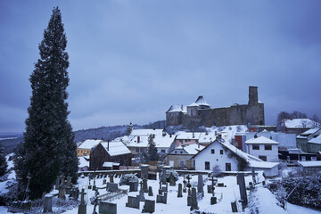Obraz premium Lipnice nad Sázavou, one of the largest castles in Czech republic, build in gothic style architecture with small pitoresque city under the castle. Picture is taken from cemetery in cold winter sunset.