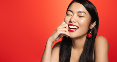 Holidays and women beauty concept. Beautiful smiling asian woman with new year christmas earrings,...
