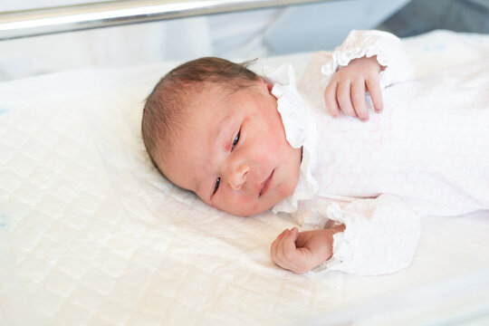 A portrait of sleepy cute newborn baby 2 days after birth.