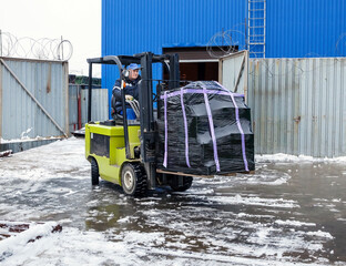 Worker on forklift transporting cargo on large modern warehouse - 530166263
