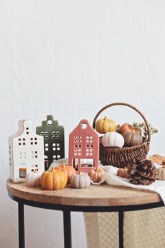 Autumn table decoration. Interior decor for fall holidays with handmade pumpkins, houses and candles. Holiday greeting card