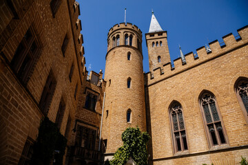 Fototapeta na wymiar Burg Hohenzollern, Baden-Wurttemberg, Germany, 5 July 2022: medieval knights castle with towers in English Gothic Revival architecture, monument to Romanticism, old fortifications on hill at sunny day