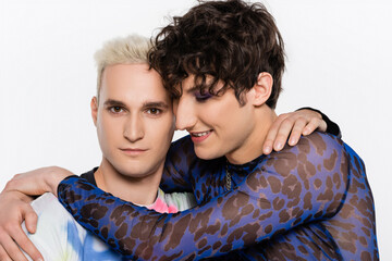 brunette queer person embracing blonde gay man isolated on grey.