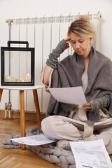 Freezing woman holding bills for electricity, gas and heating. Global energy crisis concept. Cold...