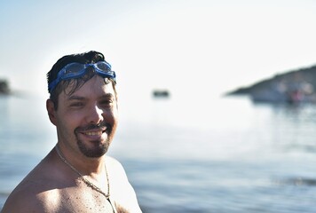 Portrait of a wet man with swimming goggles. A man swam in the sea. Island Mljet in Croatia