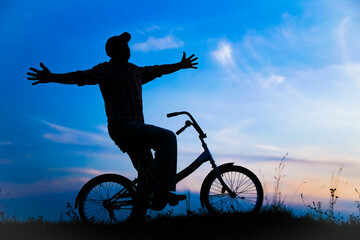 Obraz premium A Happy guy on a bike concept in the park on nature travel silhouette