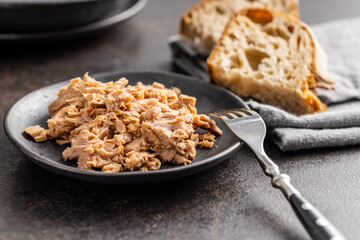 Canned tuna fish on the plate on black table.