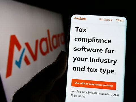 Stuttgart, Germany - 09-08-2022: Person holding cellphone with website of American software company Avalara Inc. on screen in front of logo. Focus on center of phone display.