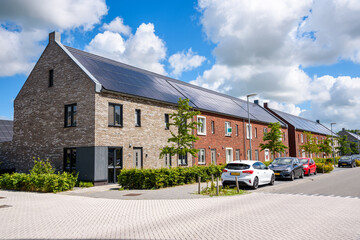 Row of new energy efficient brick terraced houses with the rooftop covered with solar panels on a...