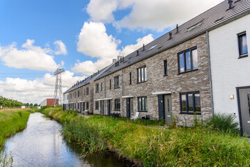 Row of new terraced houses along a canal in a suburban housing development on a sunny summer day