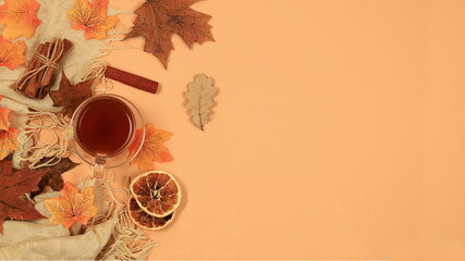 Autumn banner with hot tea in a glass cup, honey and spices on the background of seasonal flowers and leaves, space for text, cozy warm autumn concept, hygge style, selective focus, top view