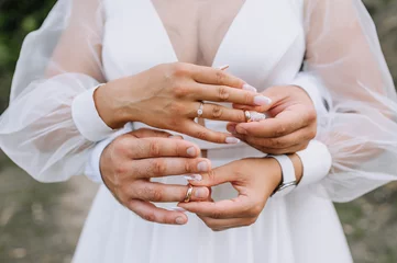 Wanddecoratie Nagelstudio Beautiful bride and groom put golden rings on their fingers at the ceremony close-up. Wedding photography, portrait.  © shchus
