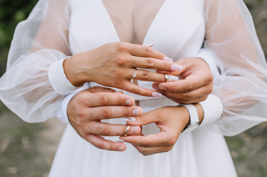 Beautiful bride and groom put golden rings on their fingers at the ceremony close-up. Wedding photography, portrait.