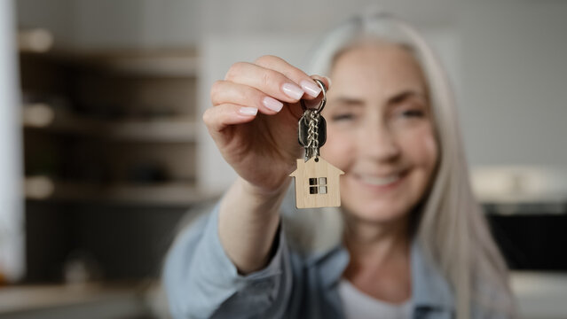 Old happy woman homeowner buyer female mature lady seller realtor tenant adult caucasian granny show bunch keys of accommodation house rental flat win new property apartment buy loan housing dwelling