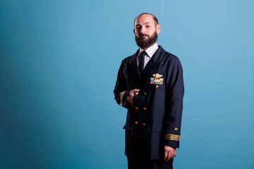 Airplane pilot wearing uniform portrait, confident plane captain standing, looking at camera, studio medium shot. Serious handsome aviator with badge on professional suit © DC Studio
