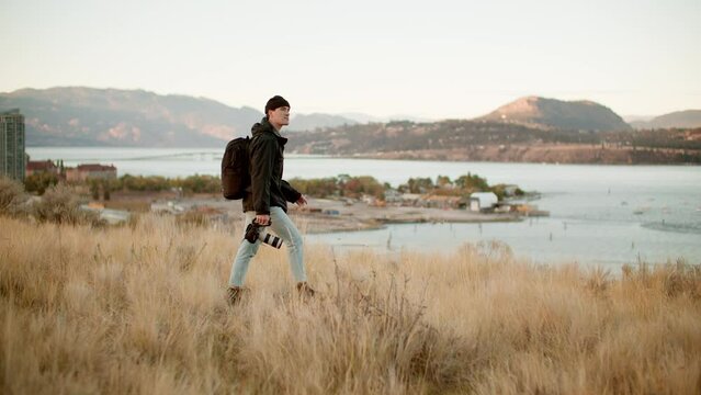 
Videographer carrying cinema camera during sunrise, wide
