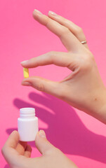 A hand takes out pills for the treatment of an illness from a jar.