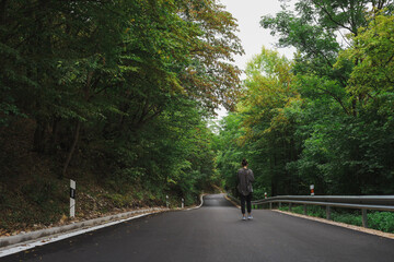 beautiful girl walks in the forest near the road