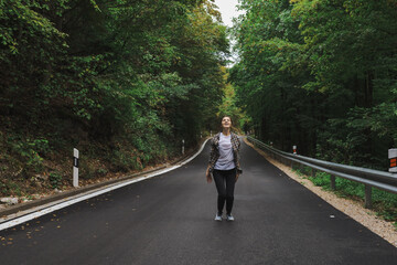 beautiful girl walks in the forest near the road