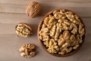 Peeled walnuts and whole walnuts in wooden bowl
