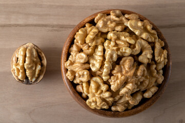 Peeled walnuts and whole walnuts in wooden bowl

