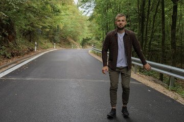 a young man is walking near the road and in the forest