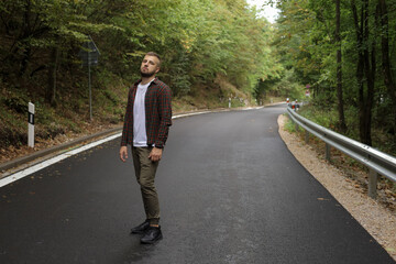 a young man is walking near the road and in the forest