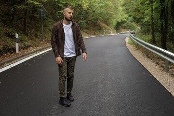 a young man is walking near the road and in the forest