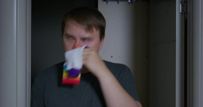Man with swollen face, red nose walks apartment, staggers from intoxication, blowing your nose in sock, unhealthy rolls pupils of his eyes. Drunk strange man has flu. Inappropriate behavior alcoholism